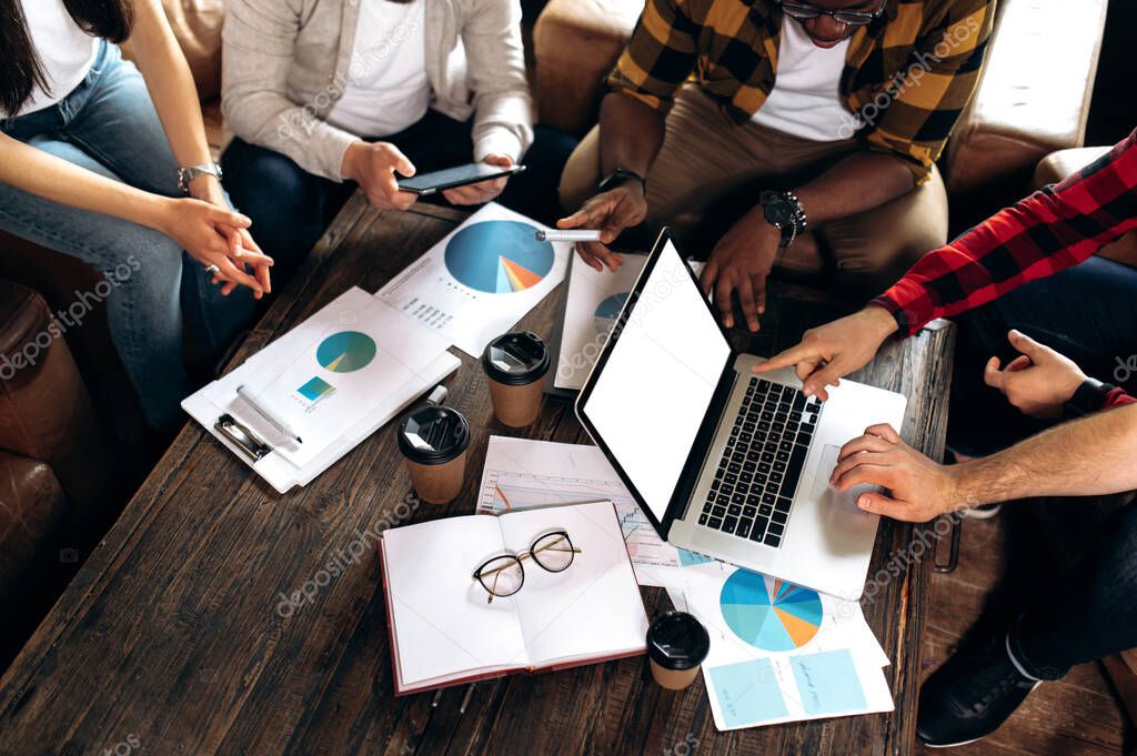 Business meeting in modern office. Coworking. The multiethnic business team gathered at the desktop, they analyze financial charts, new ideas and startups in their modern creative office