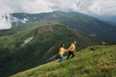 Dağlarda aşk. Aşık mutlu bir çift dağlarda el ele yürüyor ve manzaranın tadını çıkarıyor.