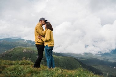 İki turist, birbirine aşık genç adam ve kadın dağın zirvesine tırmandılar, birbirlerine sarılıp eğlendiler ve harika manzaralar izlediler.