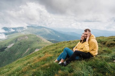 Birbirine aşık mutlu bir çift dağın tepesinde oturur ve etraflarındaki manzaranın tadını çıkarırlar.