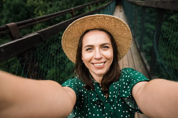 Selfie. Şapkalı, neşeli, genç, beyaz bir kadın telefonuyla selfie çekiyor.