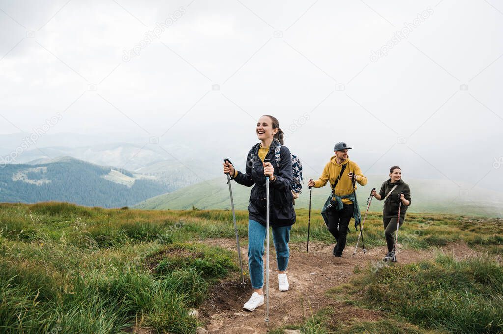 Active lifestyle. A group of young active friends went hiking in the mountains, they climb to the top of the mountain in sports gear and cheerful mood