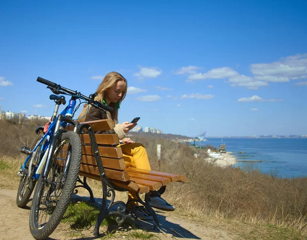A good day for an active girl is a bike, a good view, sunny weather, a seascape, a mobile phone and the Internet.