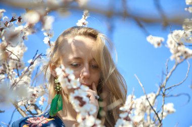 Yeşil gözlü ve sarı uzun saçlı genç, gülümseyen bir kız gözlerinin içine bakıyor. Kibar gözlerle sıcak gülümsüyor. Koyun derisi bir palto ve mavi bir gömlek giyiyor..