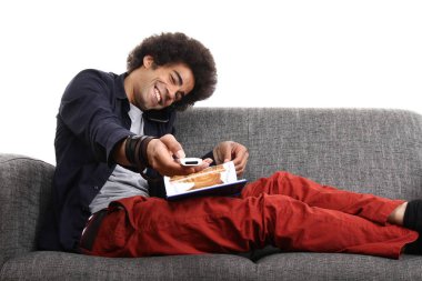 Kanepede oturan, Tv izlerken ve cep telefonu üzerinde konuşurken siyah adam