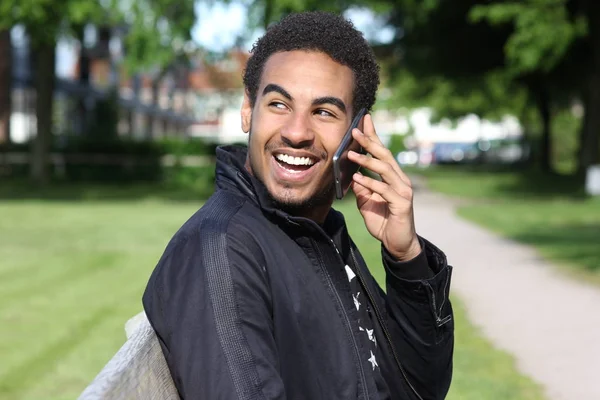 Black man sitting on bench and talking on mobile phone