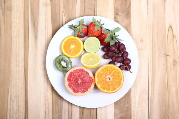 Set of fruits on plate on wooden background