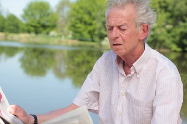 Yaşlı beyaz adam bir gazete okuyor