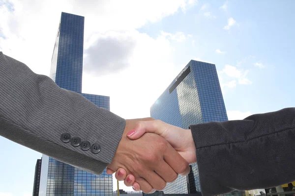 两位商人在摩天大楼的背景上握手 — 图库照片