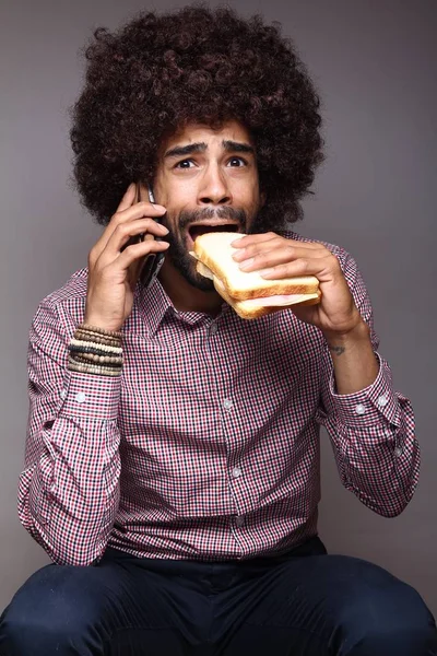 Screaming black man talking on mobile phone and eating sandwich
