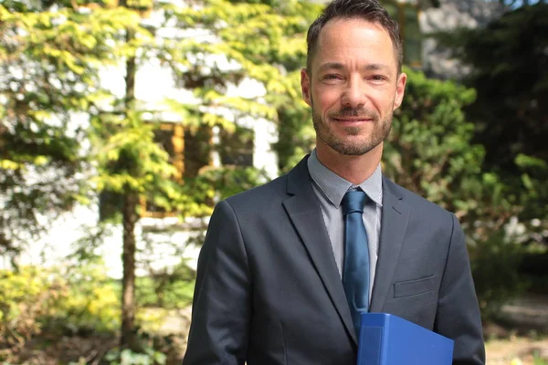 Caucasian man is holding folder and smiling outdoors