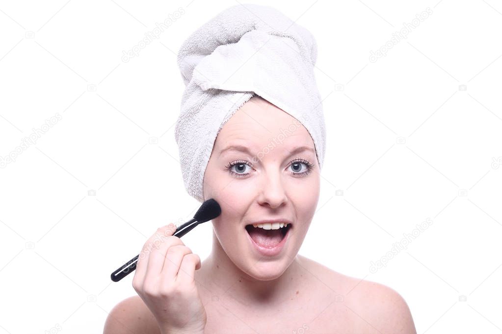 Young blonde girl is cleaning her face with face brush
