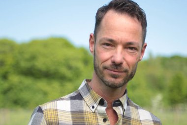 Beyaz adam açık havada gülümsüyor