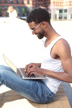 Siyah adam açık havada bir dizüstü bilgisayar kullanarak