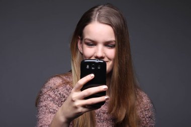 Bir cep telefonu kullanan genç sarışın kız