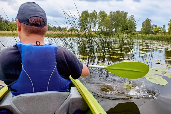 Заднього виду kayaker людина весло Байдарка на річці Стокове Зображення