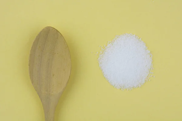 Cuchara de madera con azúcar blanca sobre amarillo — Foto de Stock