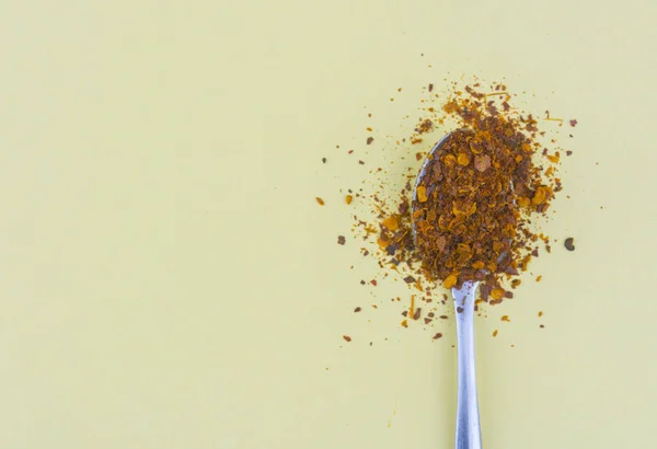 Silver spoon with Cayenne pepper on yellow — Stock Photo, Image