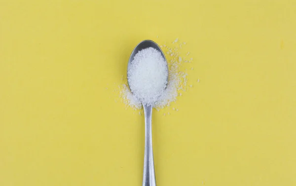 Spoon of sugar on yellow background — Stock Photo, Image