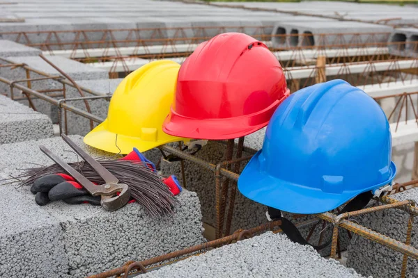 Three colorful helmets on building site