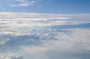 Güneşli mavi gökyüzü arka plan üzerinde bir uçak penceresinden kümülüs cennet görünümü.