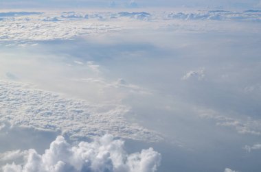 Güneşli mavi gökyüzü arka plan üzerinde bir uçak penceresinden kümülüs cennet görünümü.