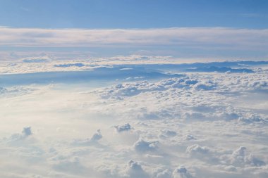 Güneşli mavi gökyüzü arka plan üzerinde bir uçak penceresinden kümülüs cennet görünümü.