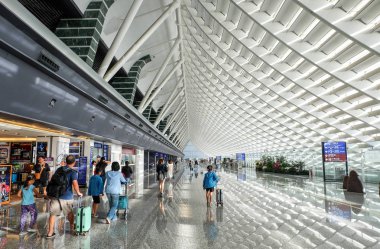 Taoyuan, Tayvan - 16 Temmuz 2018: Taoyuan Uluslararası Havaalanı'nda ana varış geçit bilgi panosu ile düz-e doğru yürüyen yolcu.