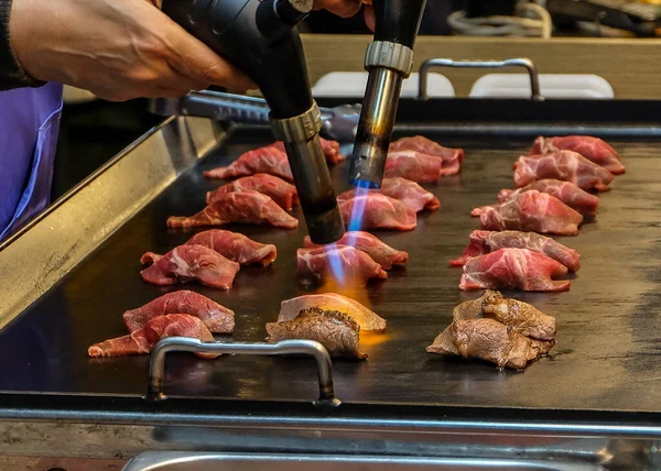 Şef sushi karamelize yapmak için bir dilim wagyu bifteğini kaynak makinesiyle yakıyor..