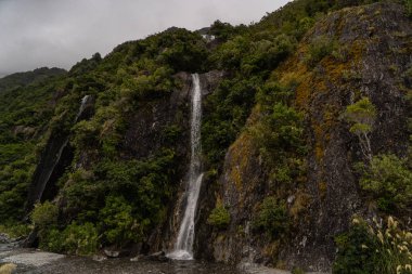 Yeni Zelanda 'daki Francis Joseph Buzulu' nda şelaleler, Yeni Zelanda 'daki Franz Josef Buzul Şelaleleri' nin yanında şelale.