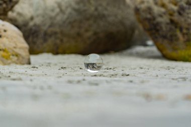 Yeni Zelanda 'daki tünel sahilinde kristal küre, arka planda kayalar, plajda lansball, Yeni Zelanda' da inanılmaz bir tünel plajı, ön planda kristal bir küre.,