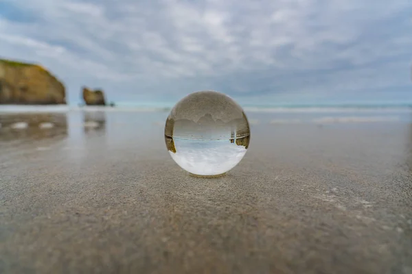 crystal ball on tunnel beach in New Zealand with rocks in the background, lansball on the beach, amazing tunnel beach in New Zealand with a crystal ball in the foreground,