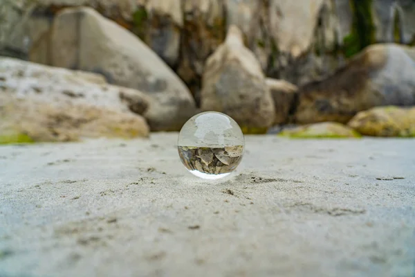 以岩石为背景的新西兰隧道海滩上的水晶球 以水晶球为前景的新西兰隧道海滩上的兰斯球 — 图库照片