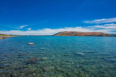 Yeni Zelanda 'daki tekapo gölü manzara fotoğrafçılığı, muhteşem mavi sulara sahip muhteşem Yeni Zelanda manzarası, arka planda alplerle muhteşem mavi sulara sahip göl.