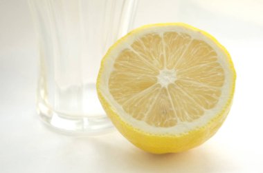 Yarım limon ve cam beyaza izole edilmiş.