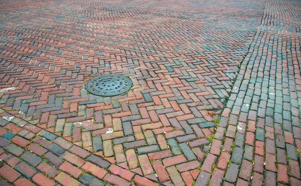 Alte Ziegelstraße Mit Einem Kanaldeckel Der Gut Abgenutzt Ist — Stockfoto