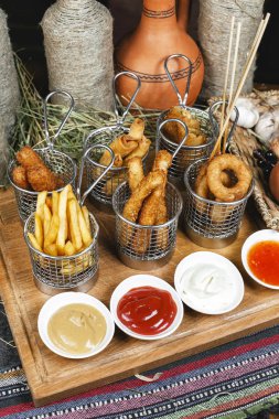 Oryantal tarzında şirket çeşitli aperatifler - soğan halkaları, şiş, patates kızartması, domates ve ekşi krema soslar bir dizi sosis