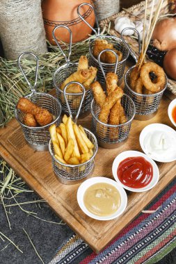 Oryantal tarzında şirket çeşitli aperatifler - soğan halkaları, şiş, patates kızartması, domates ve ekşi krema soslar bir dizi sosis