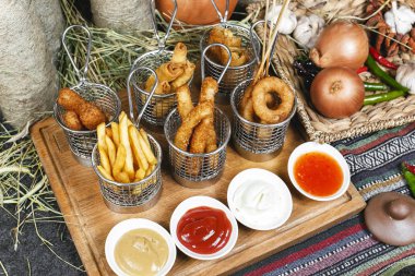 Oryantal tarzında şirket çeşitli aperatifler - soğan halkaları, şiş, patates kızartması, domates ve ekşi krema soslar bir dizi sosis