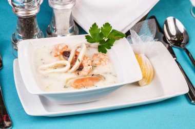 Mavi bir arka plan üzerinde Bir Akdeniz tarifine göre peynir kremalı balık, kalamar halkaları ile tavuk çorbası