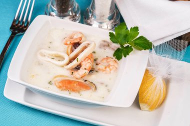 Mavi bir arka plan üzerinde Bir Akdeniz tarifine göre peynir kremalı balık, kalamar halkaları ile tavuk çorbası