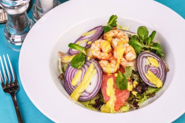 Akdeniz salatası. ızgara karides, kırmızı soğan halkaları, limon kabuğu, zencefil kökü ve zeytinyağı ile giyinmiş sebze