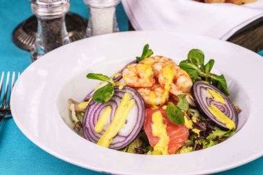 Akdeniz salatası. ızgara karides, kırmızı soğan halkaları, limon kabuğu, zencefil kökü ve zeytinyağı ile giyinmiş sebze