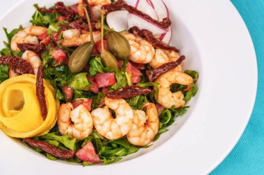 Akdeniz salatası. Arugula, domates, karides, zeytin, zeytin, fesleğen ve biberiye, zeytinyağı ve balsamik sos ile giyinmiş, limon ve biber biber ile süslenmiş