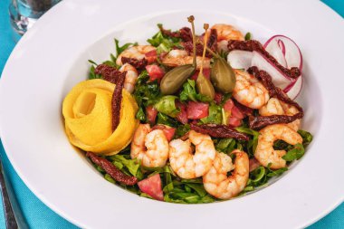 Akdeniz salatası. Arugula, domates, karides, zeytin, zeytin, fesleğen ve biberiye, zeytinyağı ve balsamik sos ile giyinmiş, limon ve biber biber ile süslenmiş