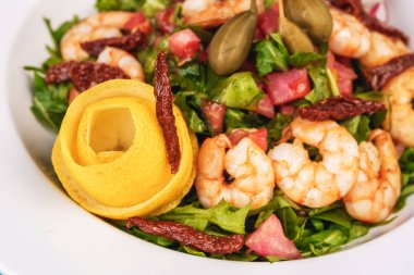 Akdeniz salatası. Arugula, domates, karides, zeytin, zeytin, fesleğen ve biberiye, zeytinyağı ve balsamik sos ile giyinmiş, limon ve biber biber ile süslenmiş