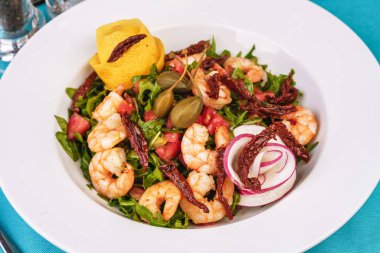 Akdeniz salatası. Arugula, domates, karides, zeytin, zeytin, fesleğen ve biberiye, zeytinyağı ve balsamik sos ile giyinmiş, limon ve biber biber ile süslenmiş