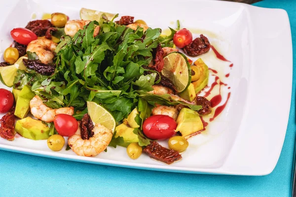 Mediterranean salad with grilled shrimps, cherry tomatoes, arugula, greens, avocado, lime, olives, balsamic sauce