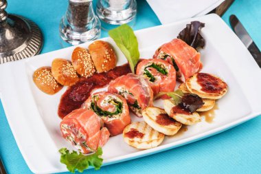 Biber soslu peynir ve yeşillikli Akdeniz somon ruloları, krep ve çöreklerle servis edilir