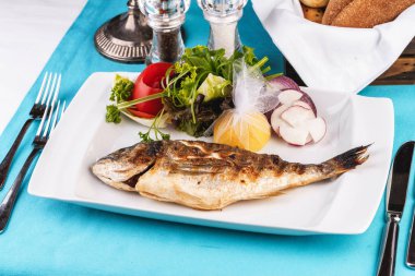 Akdeniz yemeği, Avrupa mutfağı. fırında pişmiş bütün balık, sebze, yeşillik, arugula, soğan halkaları, domates ve limon bir salata ile servis